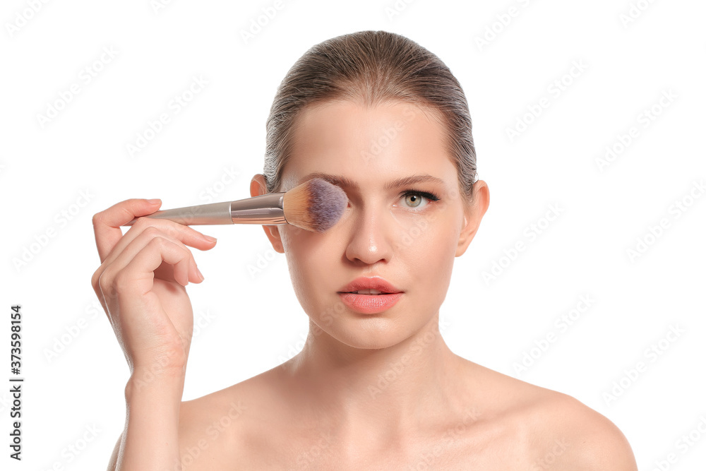 Fototapeta premium Beautiful young woman with makeup brush on white background