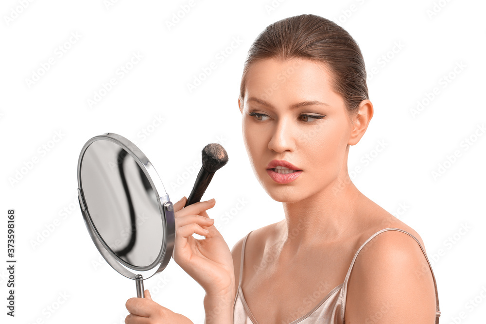 Beautiful young woman applying makeup against white background Beautiful young woman applying makeup against white background