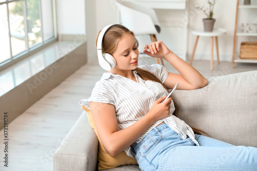 Sleepy young woman listenin...