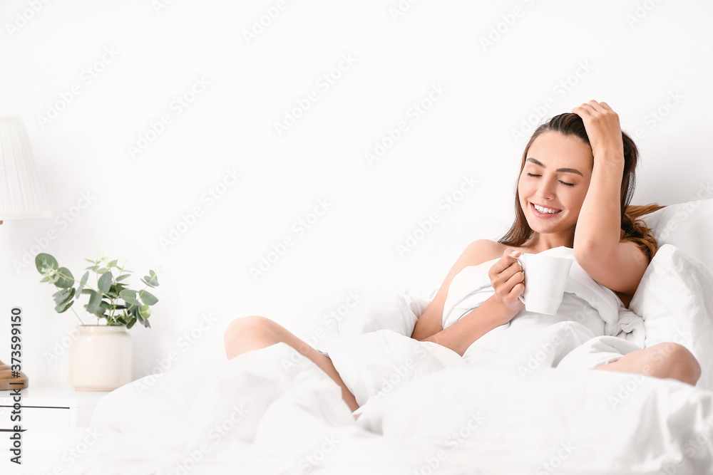 Seductive woman drinking coffee in bed at home