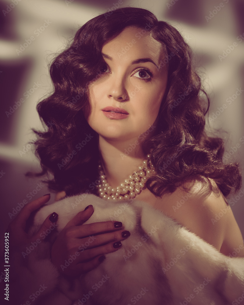 Portrait of luxury fashion woman in fur coat and pearls showing shoulder. image toned in warm colors in retro style