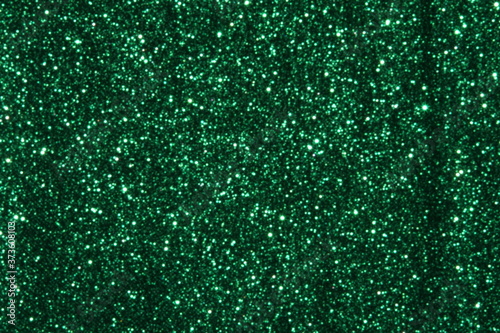 Green Sparkling Lights Festive background with texture. Abstract Christmas twinkled bright bokeh defocused and Falling stars. Winter Card or invitation 