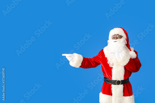 African-American Santa Claus showing something on color background