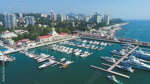 Beautiful summer air flight over the city of Sochi and the sea port. Expensive yachts and boats at the pier. City attraction. Luxury vacation. Panorama of the city on the beach.