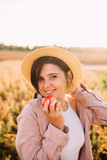 a girl in a straw hat in a field with an apple