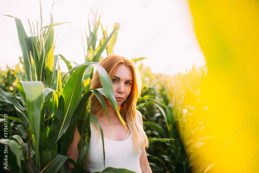Fototapeta premium red-haired girl smiles in a cornfield