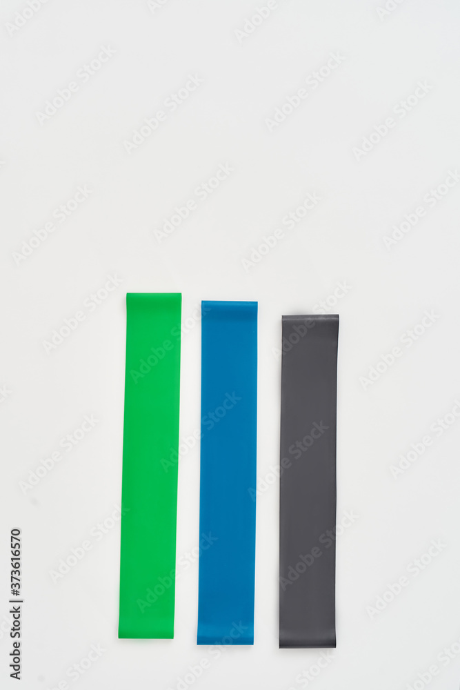 Training with elastic expander. Three different colors fitness resistance bands isolated on grey background Training with elastic expander. Three different colors fitness resistance bands isolated on grey background