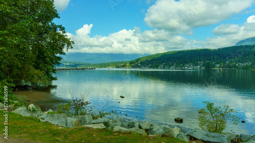 Tranquil view from public park across ocean inlet with forested hills and mountains in background