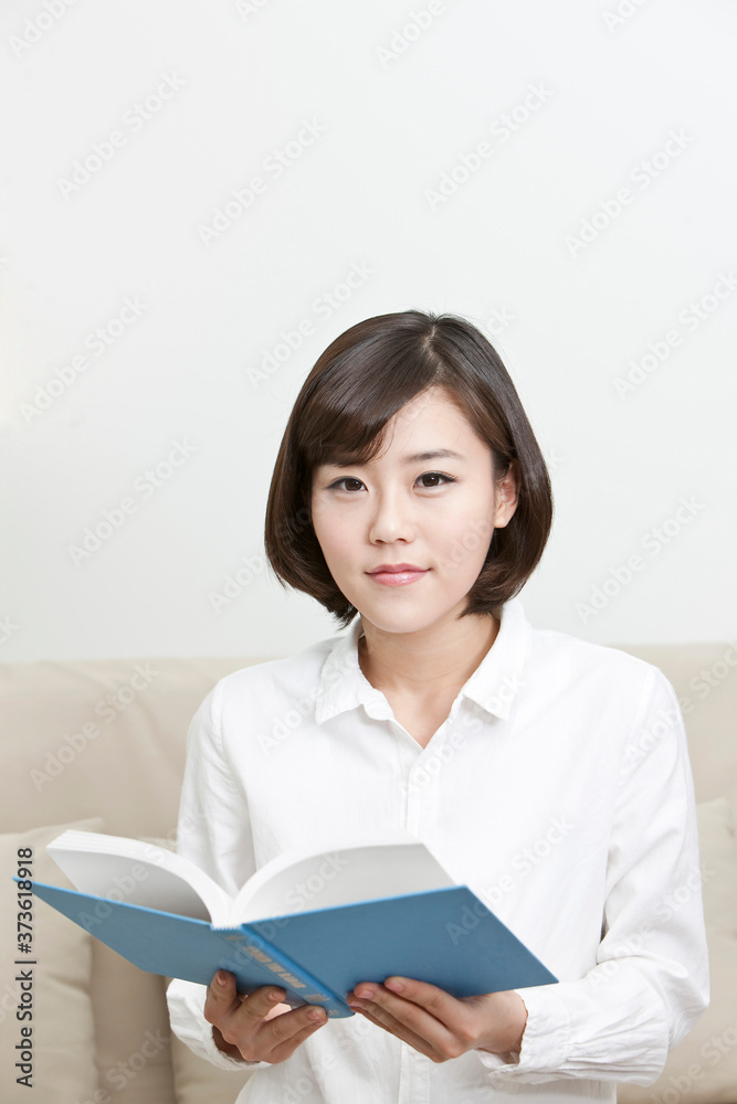 young woman reading a book sitting on a sofa young woman reading a book sitting on a sofa