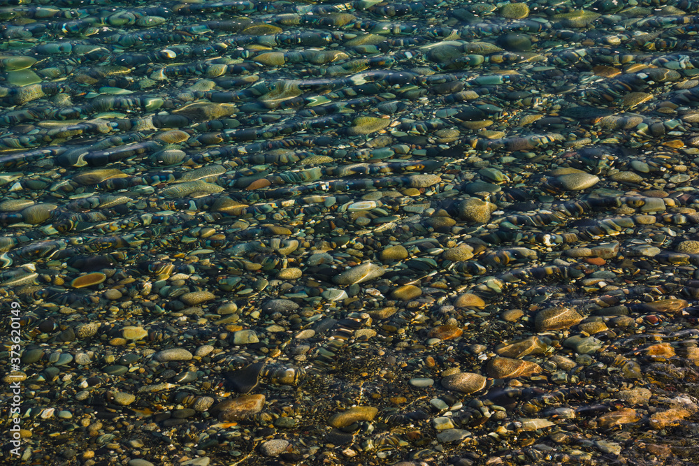 Natural ripple and rainbow effect on a beach of stones and pebbles photographed through shallow water close to the shore at Annalong, County Down, Northern Ireland. Natural ripple and rainbow effect on a beach of stones and pebbles photographed through shallow water close to the shore at Annalong, County Down, Northern Ireland.