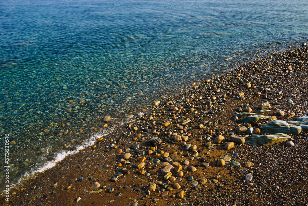 A sloping beach of stones and shingle is lapped by the sparkling transparent waters of the clear blue Irish Sea at Annalong, County Down, Northern Ireland. A sloping beach of stones and shingle is lapped by the sparkling transparent waters of the clear blue Irish Sea at Annalong, County Down, Northern Ireland.