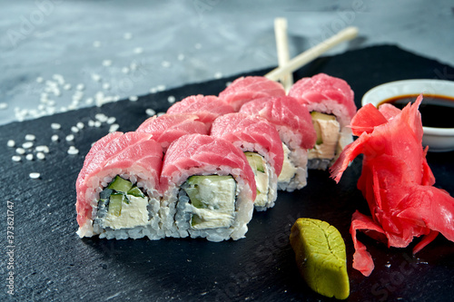 Appetizing Japanese sushi rolls - Philadelphia with cream cheese, cucumber and tuna on a black board on a gray background