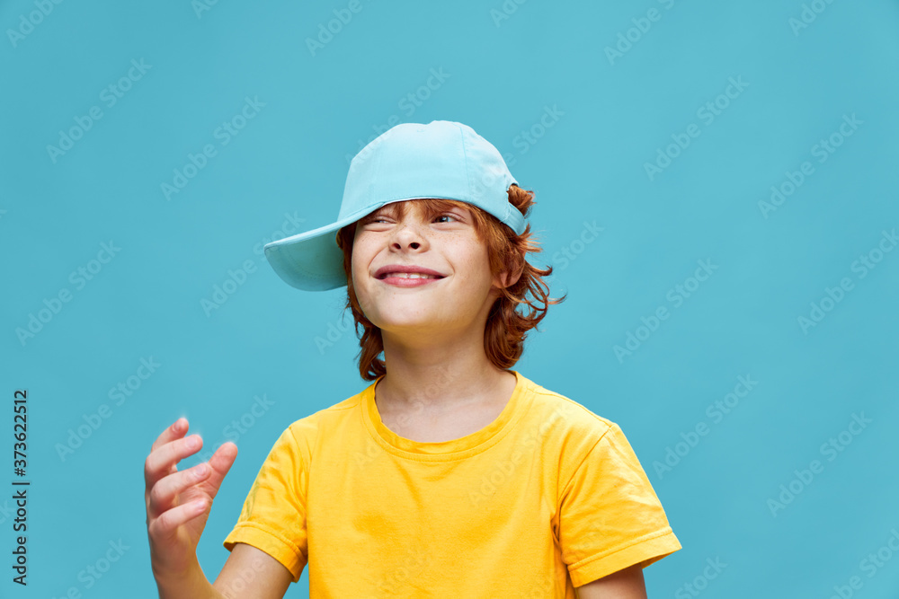 cheerful child with a cap on his head laughs and looks towards a yellow T-shirt cheerful child with a cap on his head laughs and looks towards a yellow T-shirt