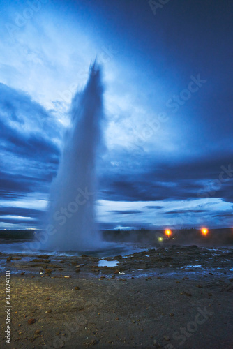 Geysir night landscape in Iceland emits huge column of hot water and steam into the air