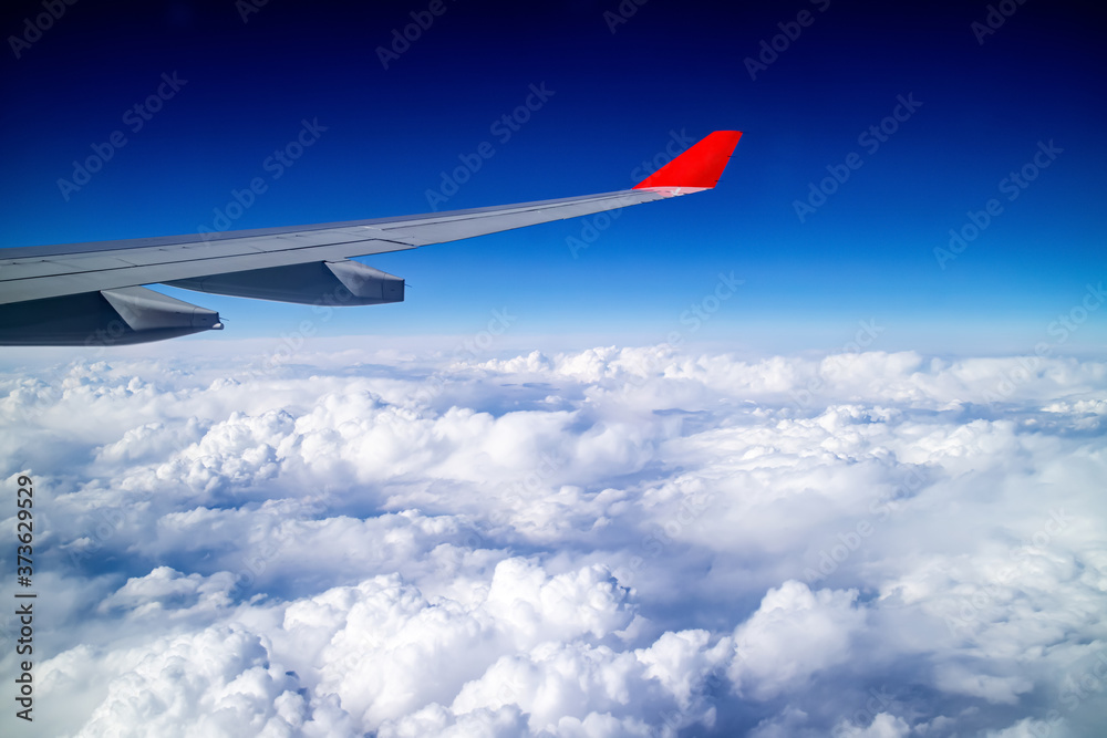 Airplane wing and aerial view during flight with clear blue sky and clouds Airplane wing and aerial view during flight with clear blue sky and clouds