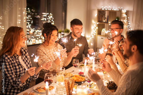 Photography holidays, celebration and people concept - happy friends with sparklers having c