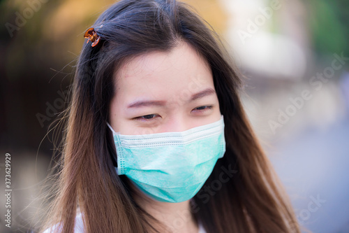 Candid Portrait a young Asian woman wearing a green medical face mask protection. Long hair people. Concept of new living in the time (New normal) of emerging epidemics coronavirus (Covid-19).