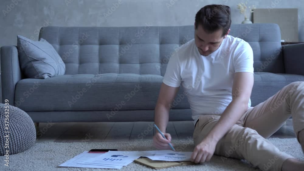 Male works with paper documents, male freelancer work in modern living room doing paperwork