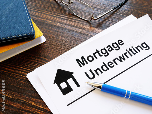Information about mortgage underwriting and pen on the table. photo