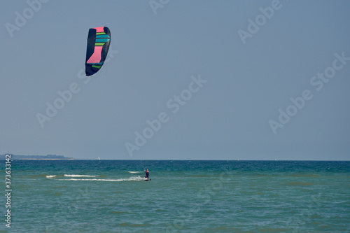 Brunette woman kitesurfing or kite boarding towards the camera on a sunny summer day in a front view to the camera