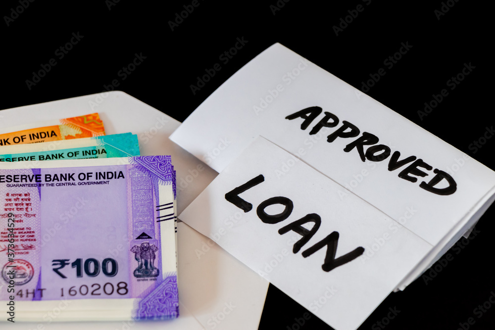 APPROVED & LOAN words written on white paper with money shot on black background. APPROVED & LOAN words written on white paper with money shot on black background.