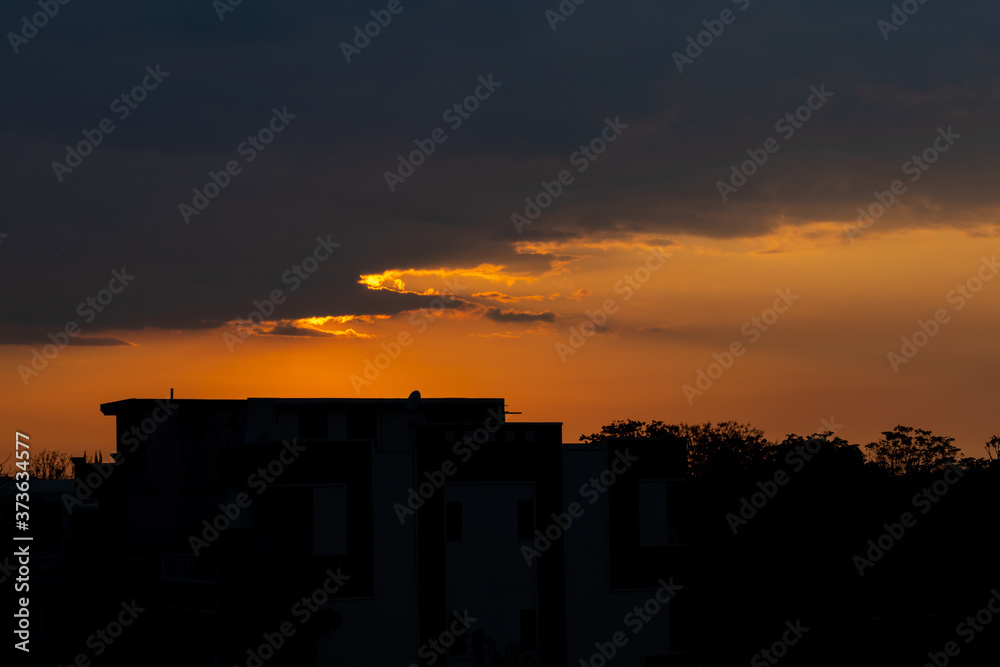 Beautiful silhouette shot of a house building against setting sun in the background.