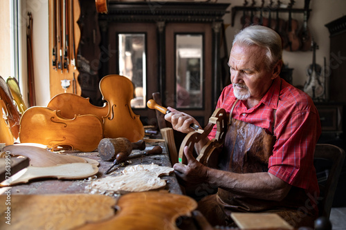 Arts and crafts. Senior carpenter craftsman carving wood in his old-fashion workshop. An experienced caucasian elderly man manually making masterpiece. Handcraft and creativity.