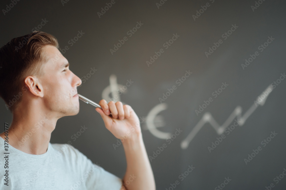 Fototapeta premium Smiling young man holding a folder with documents in his hands on the background of drawn business sketches