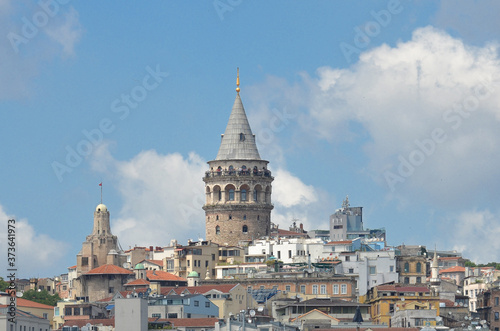 Istanbul cityscape including historical Galata Tower, Boshphorus, passenger boats, and bridge

