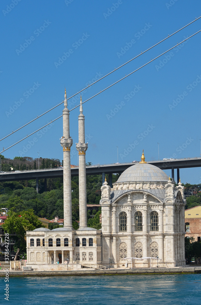 Naklejka premium Istanbul cityscape, including Bosphorus bridge and Ortakoy Mosque as seen from a passenger boat - Istanbul, Turkey