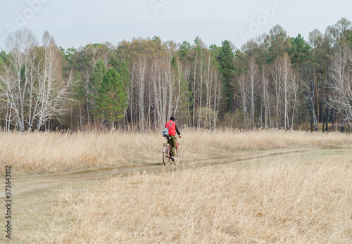 man rides a bicycle on a forest road, view from the back