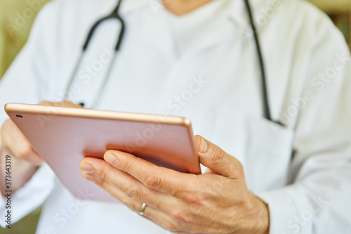 Arzt in Klinik schaut nutzt App auf Tablet Computer