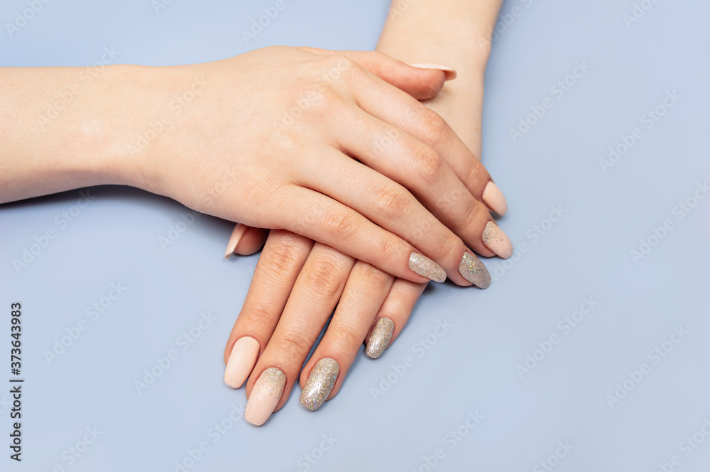 Beautiful well-groomed hands with manicure and nail polish. Blue pastel background. Close-up. Beautiful well-groomed hands with manicure and nail polish. Blue pastel background. Close-up.