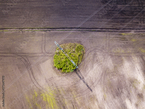 Aerial drone view. A power line post among a plowed field. Sunny spring day.