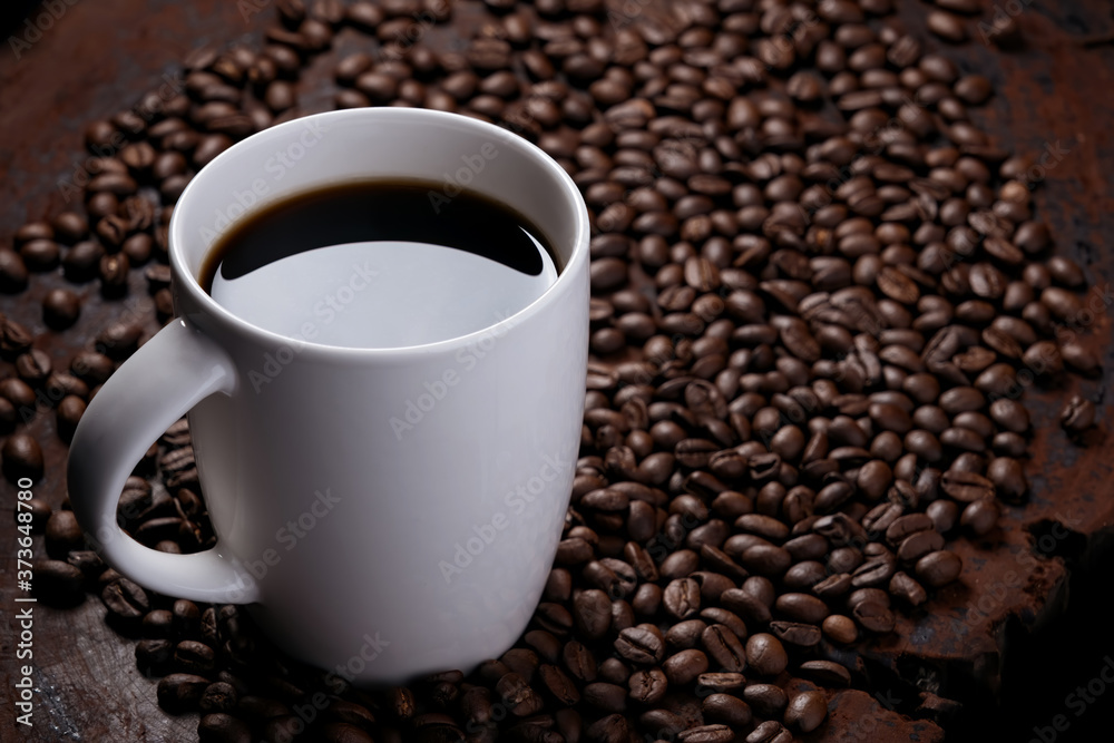 black coffee in white mug with surrounded by roasted coffee beans on dark red wood table black coffee in white mug with surrounded by roasted coffee beans on dark red wood table