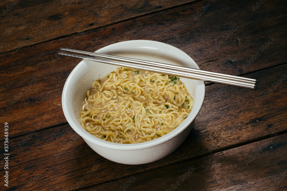 cooked instant noodle in white bowl with standless steel chopsticks on wooden table cooked instant noodle in white bowl with standless steel chopsticks on wooden table