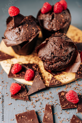chocolate cupcakes with raspberries and bitter chocolate close-up on a light background