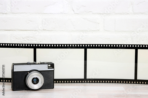 Old retro camera with  camera film agianst white brick wall. photo