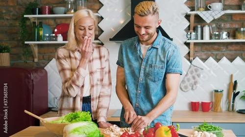 Smiling young couple cooking together vegetarian meal in the kitchen at home