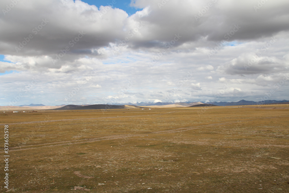 View of mountains, grassland, Nomadic tents and Namtso Lake with the dramatic sky in Tibet, China