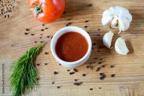 ketchup in a bowl, fresh tomato, dill sprig and whole tomato close-up..