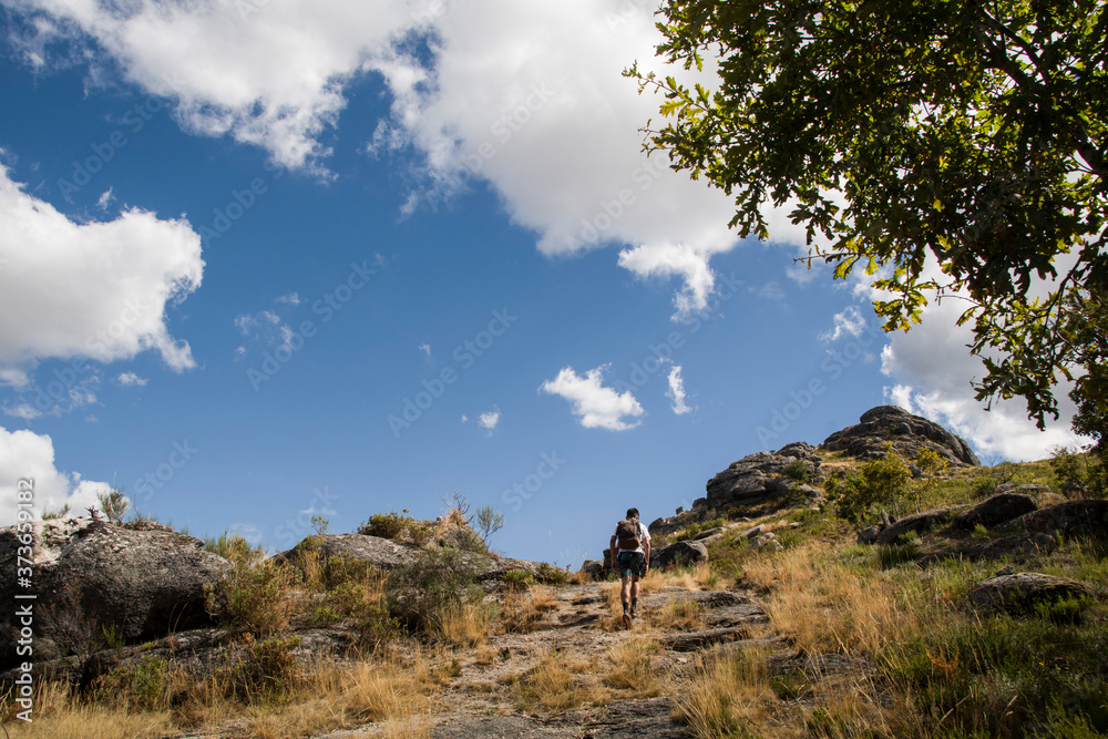 Hiker going uphill under a blue sky Hiker going uphill under a blue sky