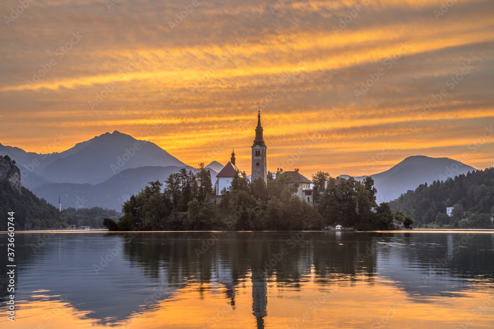 Lake bled with church during orange morning sky