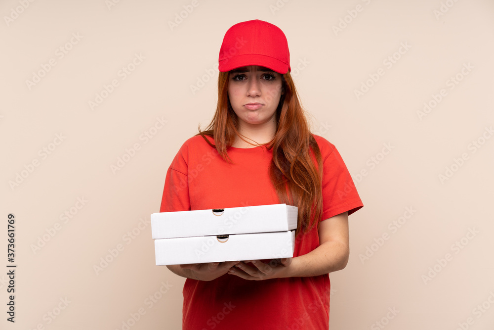 Pizza delivery teenager girl holding a pizza over isolated background sad Pizza delivery teenager girl holding a pizza over isolated background sad