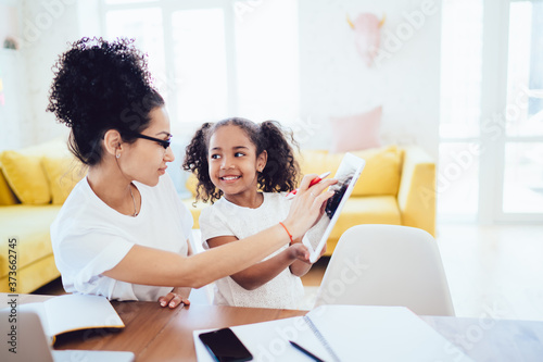 Ethnic daughter showing screen of tablet to mother