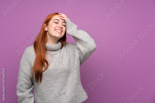 Redhead teenager girl over isolated purple background laughing
