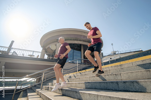 Bearded male and mature grey-haired male exercising, running down stairs
