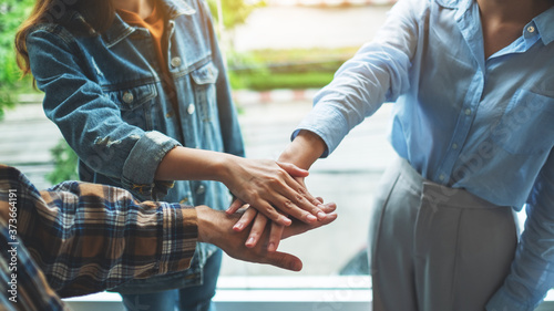 Closeup image of business team standing and joining their hands together in office