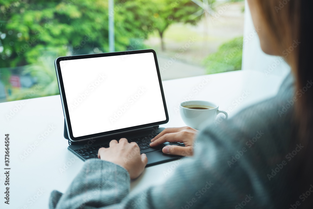 Mockup image of a businesswoman using and typing on digital tablet keyboard with blank white desktop screen as a computer pc in office Mockup image of a businesswoman using and typing on digital tablet keyboard with blank white desktop screen as a computer pc in office