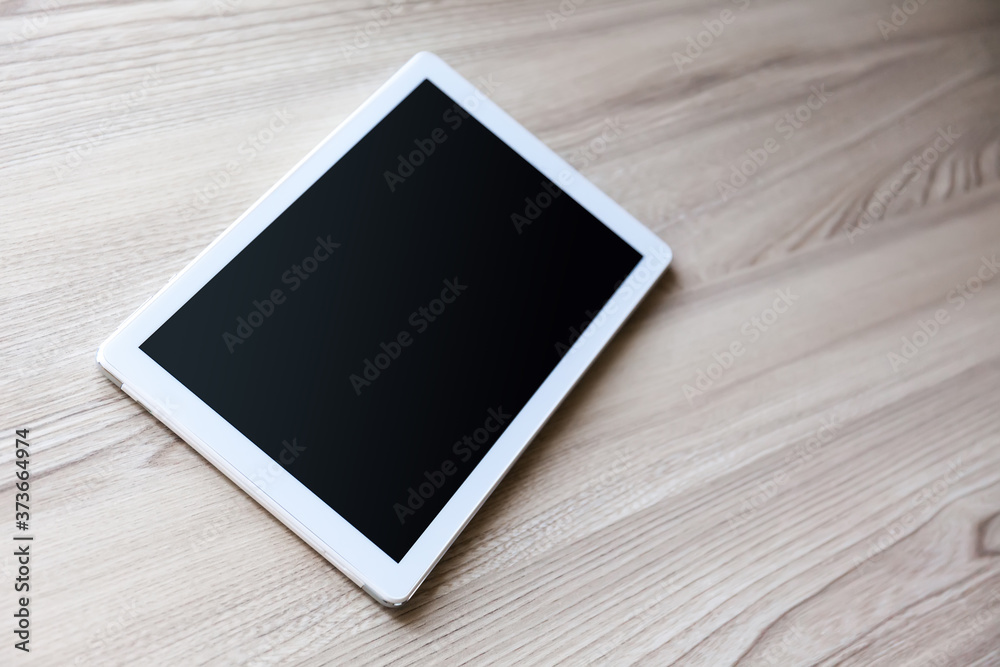 White tablet pc with empty screen on wood background White tablet pc with empty screen on wood background